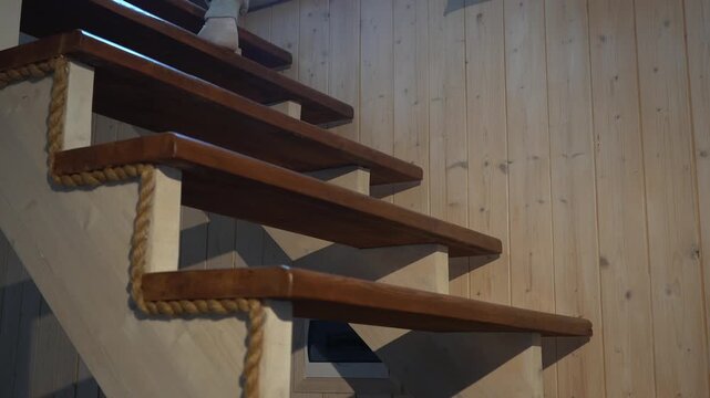 A beautiful young woman climbs the stairs in a country house. Close-up of her legs.