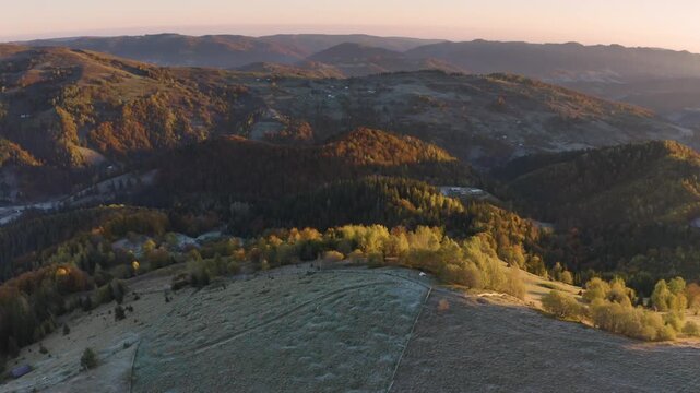 Ukraine, drone, flight in the Carpathians early in the autumn morning at sunrise near the city of Kosiv. Bright forests and dwellings of the Hutsul highlanders on the glades