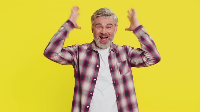 Caucasian middle-aged man celebrating success victory, winning birthday lottery jackpot goal achievement, play game, good positive news, triumph. Mature adult guy isolated on yellow background indoors