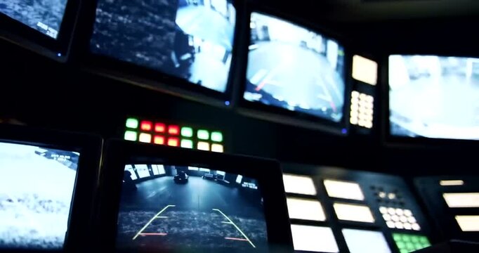Control room with multiple monitors displaying surveillance footage of parking lot