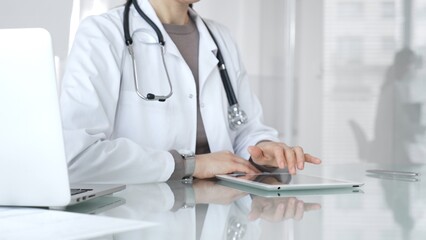 Doctor using digital tablet for medical consultation, viewing health records in modern hospital clinic setting. Medicine and health care