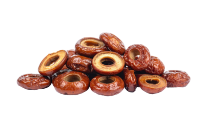 Heap of brown, dried, pitted, ring-shaped fruit sections against a stark black backdrop, with glossy surfaces