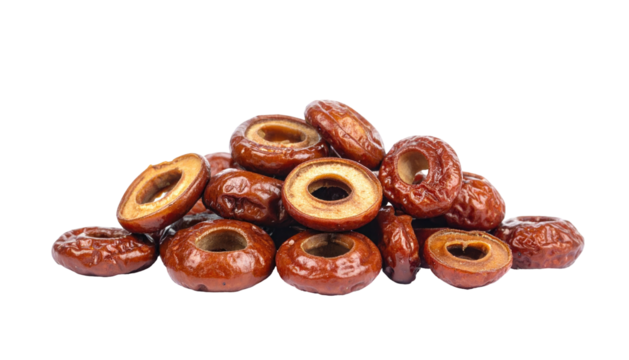 Heap of brown, dried, pitted, ring-shaped fruit sections against a stark black backdrop, with glossy surfaces