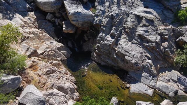 toma cenital de dron de un oasis con agua rodeado de un entorno rocoso en medio del desierto de Sonora, el lugar se llama Las tinajas.