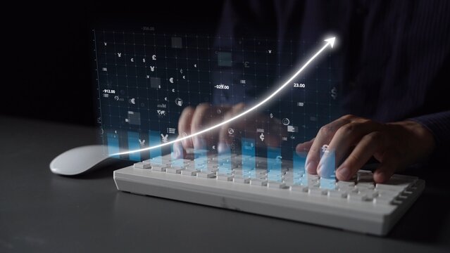 A person uses a white keyboard while digital graphs and arrows emerge, symbolizing innovation and growth in technology and business analytics in a modern workspace. Copula