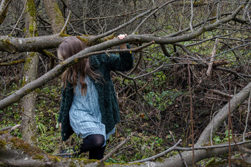 Woman stepping among fallen trees in leafless forest, Dubrovitsky Forest, November