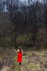 Woman in red dress standing at edge of leafless forest, Dubrovitsky Forest, November