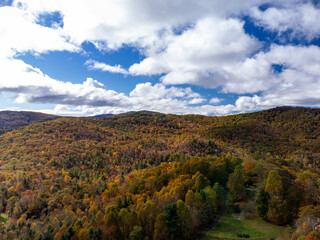 Rolling hills of North Carolina glow with peak autumn color beneath a bright sky near the Blue Ridge Parkway.
