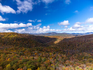 Rolling hills of North Carolina glow with peak autumn color beneath a bright sky near the Blue Ridge Parkway.