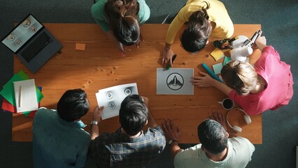 Top view of business team put graphic logo on meeting table with laptop and paper and start to design while explain idea. Manager explaining concept art while placed logo on meeting table. Symposium.