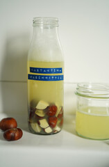 Natural detergent prepared from horse chestnuts in a clear glass bottle with light brown liquid. Organic, plant-based cleaning concept. German text on the label.