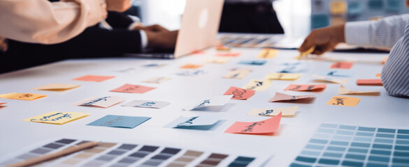 Naklejka na ściany i meble A dedicated team engages in a brainstorming session, utilizing sticky notes and laptops in a modern office environment to drive creativity and project planning. SACTR