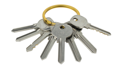 Bunch of silver keys hanging on a golden ring, isolated on a black background, showing various key shapes