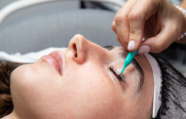 A client lies on a treatment table with their eyes closed during a lash lift procedure