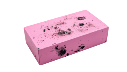 Worn pink eraser with smudges, resting on black. Slightly angled perspective shows its rounded edges and imperfections