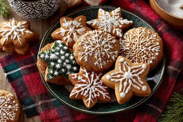 Fototapeta premium Decorated Gingerbread Cookies with White Icing Snowflake Designs on Green Ceramic Plate Plaid Tablecloth