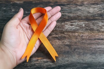 Hand holding an orange awareness ribbon, symbolizing support for leukemia, multiple sclerosis, kidney cancer, and other conditions