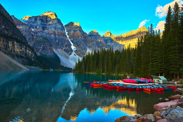 Canoes on Crystal Lake at Sunrise with Majestic Mountains and Pine Forest Reflections