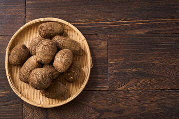 里芋（泥付き）を竹籠に盛った和風の食材カット