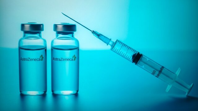 Two vials of astrazeneca vaccine and a syringe on a blue background - Powered by Adobe