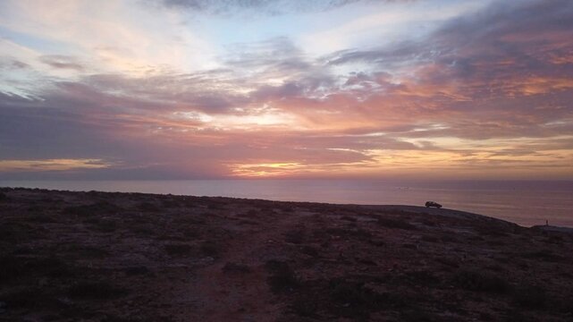 Car Parked on Remote Cliff Overlooking Dramatic Ocean Sunset