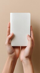 Hands Holding a Plain Notebook on a Beige Background