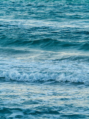 A beautiful and simple background of the blue green sea surface with gentle waves and white foam creating a soft horizontal pattern