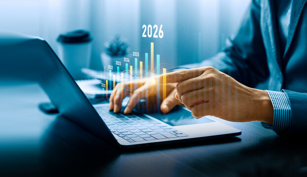 Business growth and financial projection concept for 2026 with businessman analyzing bar chart and data on laptop, showing increasing profit trend, investment success, strategic economic development
