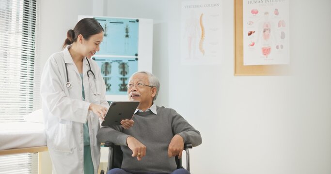 Asian female doctor using a digital tablet to explain health information to an elderly male patient, incorporating AI-assisted tools for better diagnosis, data analysis, and patient understanding.