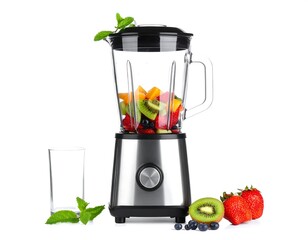 A blender filled with fruits and a glass beside it, ready to blend