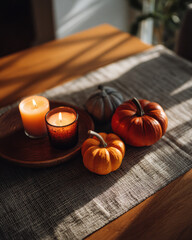 Cozy autumn scene featuring candles and pumpkins on wooden table, creating warm and inviting atmosphere