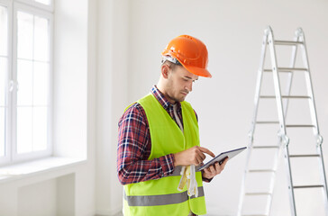 Foreman professional male worker using tablet computer to supervise personnel and direct, check...