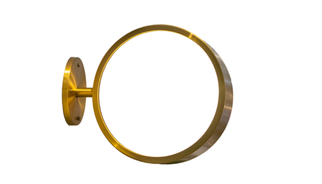 A golden, circular sign with a blank, white face and wall mount against a black background