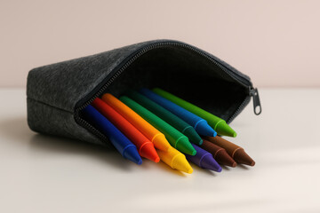 Colorful crayons arranged in a grey pencil case on white table, organized supplies for creative education and artistic drawing activities