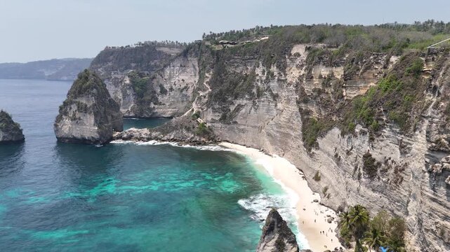 Aerial view of young lady on the cliff of Diamond Beach, Nusa Penida, Bali. Indonesia