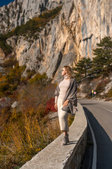 Woman Scenic Autumn Roadside View; Solo female traveler admires mountain landscape during fall near a road in Europe; showcasing tranquility and nature.