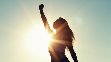 Strong confident woman! Winning and life goals concept. Empowered woman celebrating against a vibrant sunset backdrop.