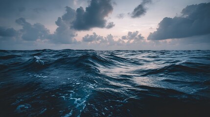Dark ocean waves surge beneath an overcast and moody twilight sky
