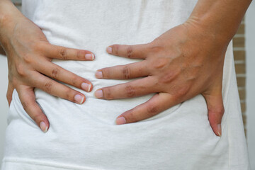 Lower back pain from overwork. Hands on lumbar area suggest strain or fatigue. Ideal for ads on posture care, physiotherapy, or pain relief.