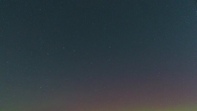 Time-lapse video of a starry night sky with faint aurora borealis fading into darkness. Peaceful celestial scene with shooting stars and smooth night transition