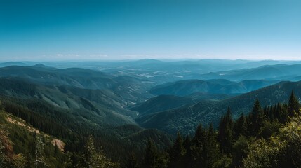 Expansive view across layers of forested mountains under a clear bright sky