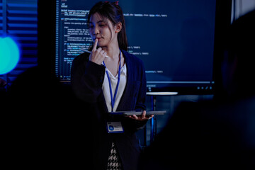 An Indian female developer leads a code review, holding a report. She explains a Python script for an AI or cybersecurity system to her team in a dark SOC Security Operations Center