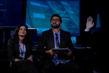 A diverse IT team, including an Indian man and woman, in an urgent security briefing. They are focused, listening to an update on a critical data incident or system failure.