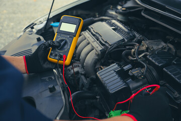Mechanic uses electrical meter to check battery low energy problem for car care service maintenance and re charger or jump start or change battery replacement.