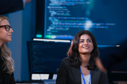 Two female tech leaders, one Indian and one Caucasian, focus on a presentation about future strategy. They are planning sustainable AI innovation and ESG goals for growth.