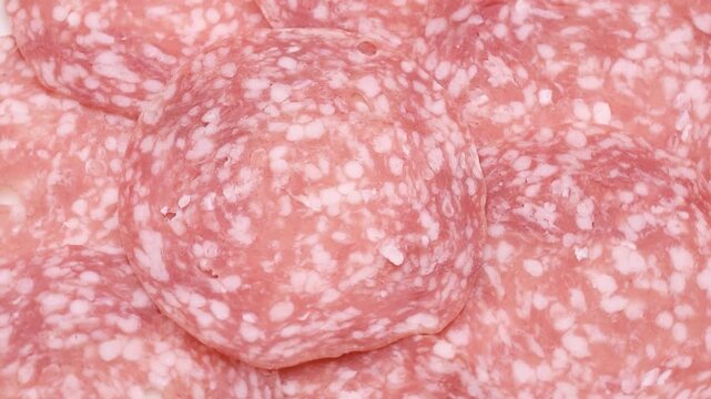 Rotating close-up video of Milano-style salami slices, showing detailed texture and marbling, traditional Italian charcuterie.