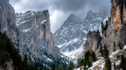 Towering alpine rock faces loom over a narrow valley floor covered in sparse snow and evergreen trees