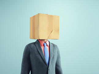 Businessman with a cardboard box head poses against a light blue background in a quirky representation of modern identity