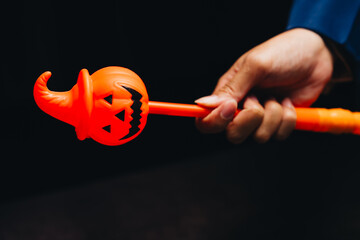 Bright orange Halloween wand with pumpkin design held by hand in festive setting, perfect for Halloween celebrations and events