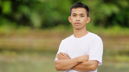Young indonesian man in rural indonesia looking at camera, serious face, authentic portrait,...